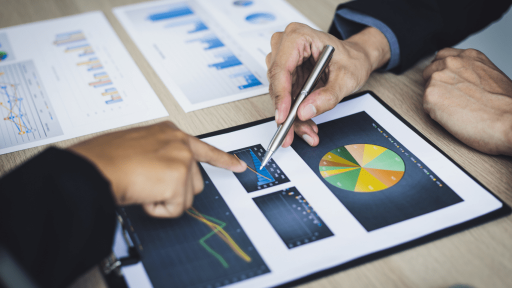 two business people sitting at a table with graphs and papers