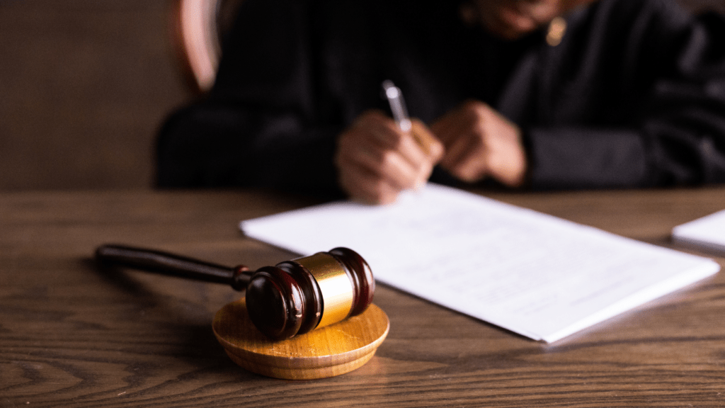 A lawyer holding a book and pen on a desk with a gavel in the background