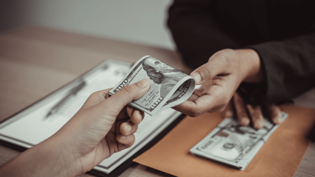 a person is counting money in front of a desk