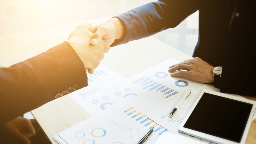 two business people shaking hands over a desk