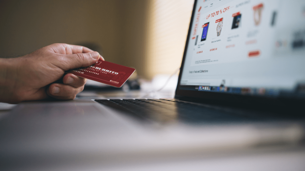 a person sitting on a couch holding a credit card and a laptop