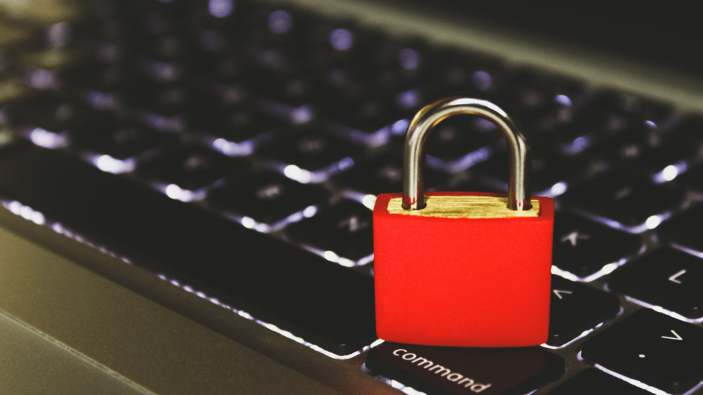 a red padlock sits on top of a laptop keyboard