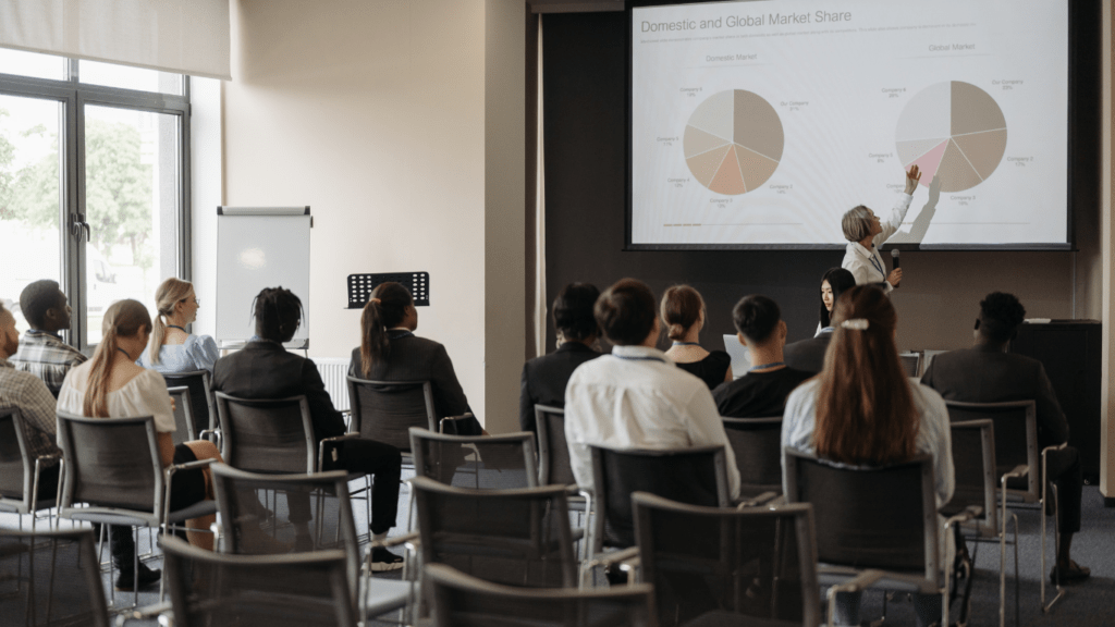 a group of people in a meeting room looking at a presentation on a large screen