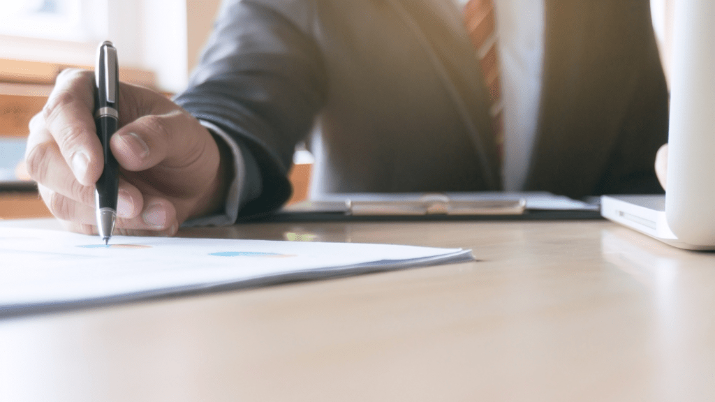 a person in a suit is writing on a piece of paper