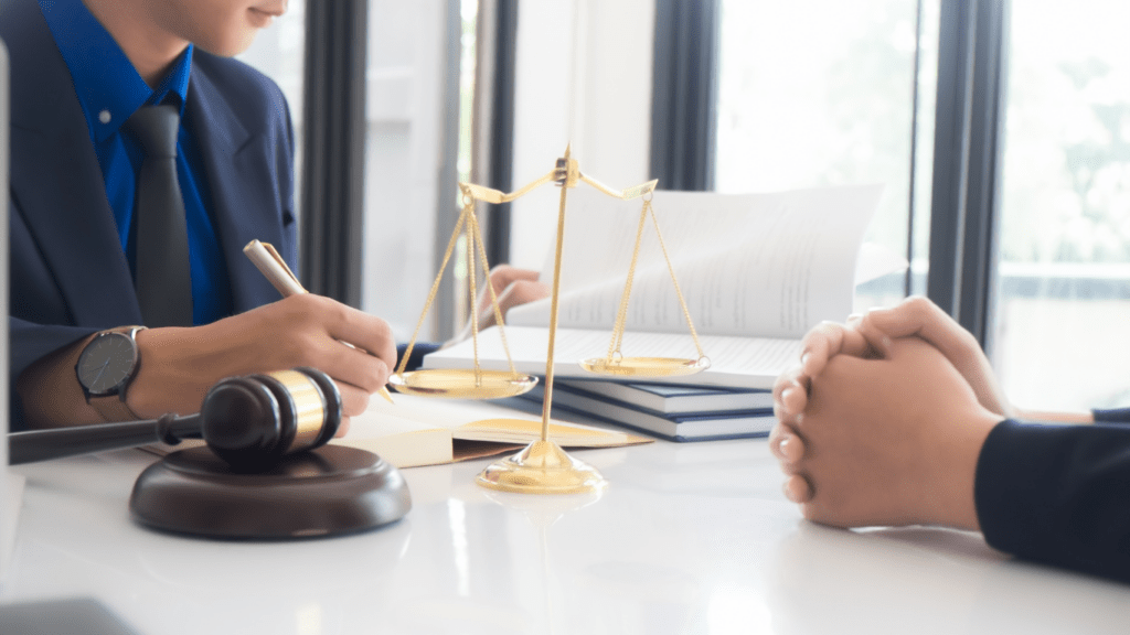 a person in a suit sitting at a desk with a scale of justice