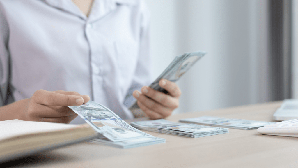 a person is counting money in front of a desk