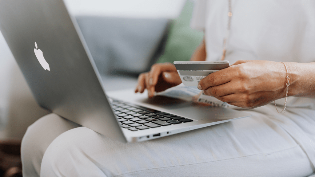 a person sitting on a couch holding a credit card and a laptop