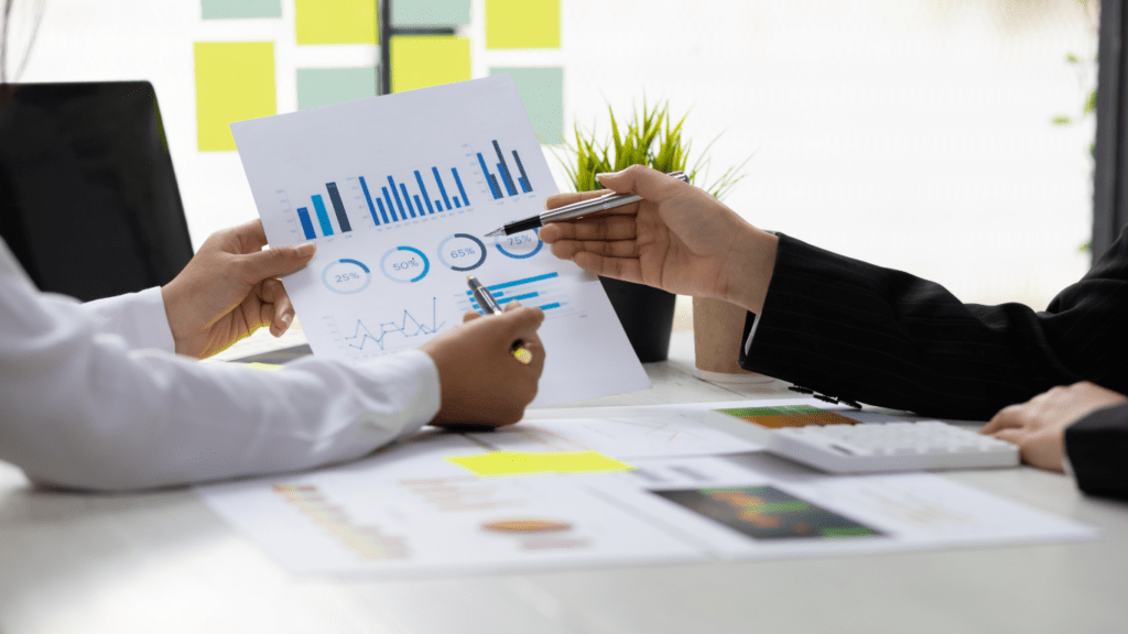 two business people sitting at a table with graphs and papers